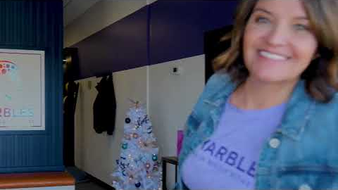 Smiling trainer at Marbles Fitness gym entrance